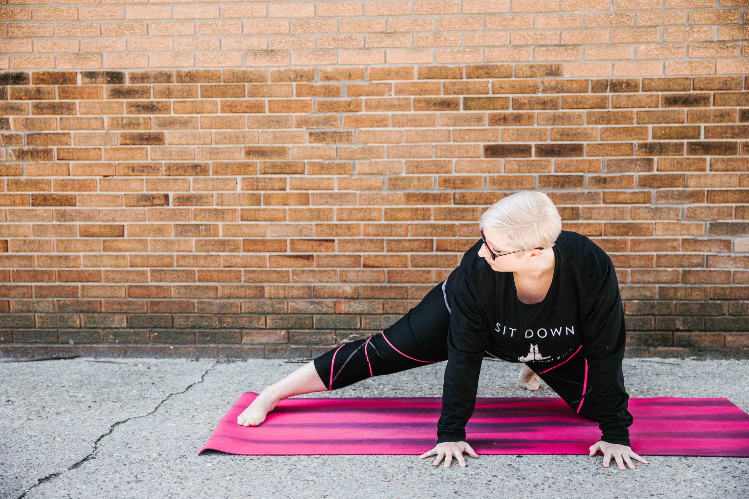 Marta Gruber, a white woman silouhetted by a window practices pranam pose.