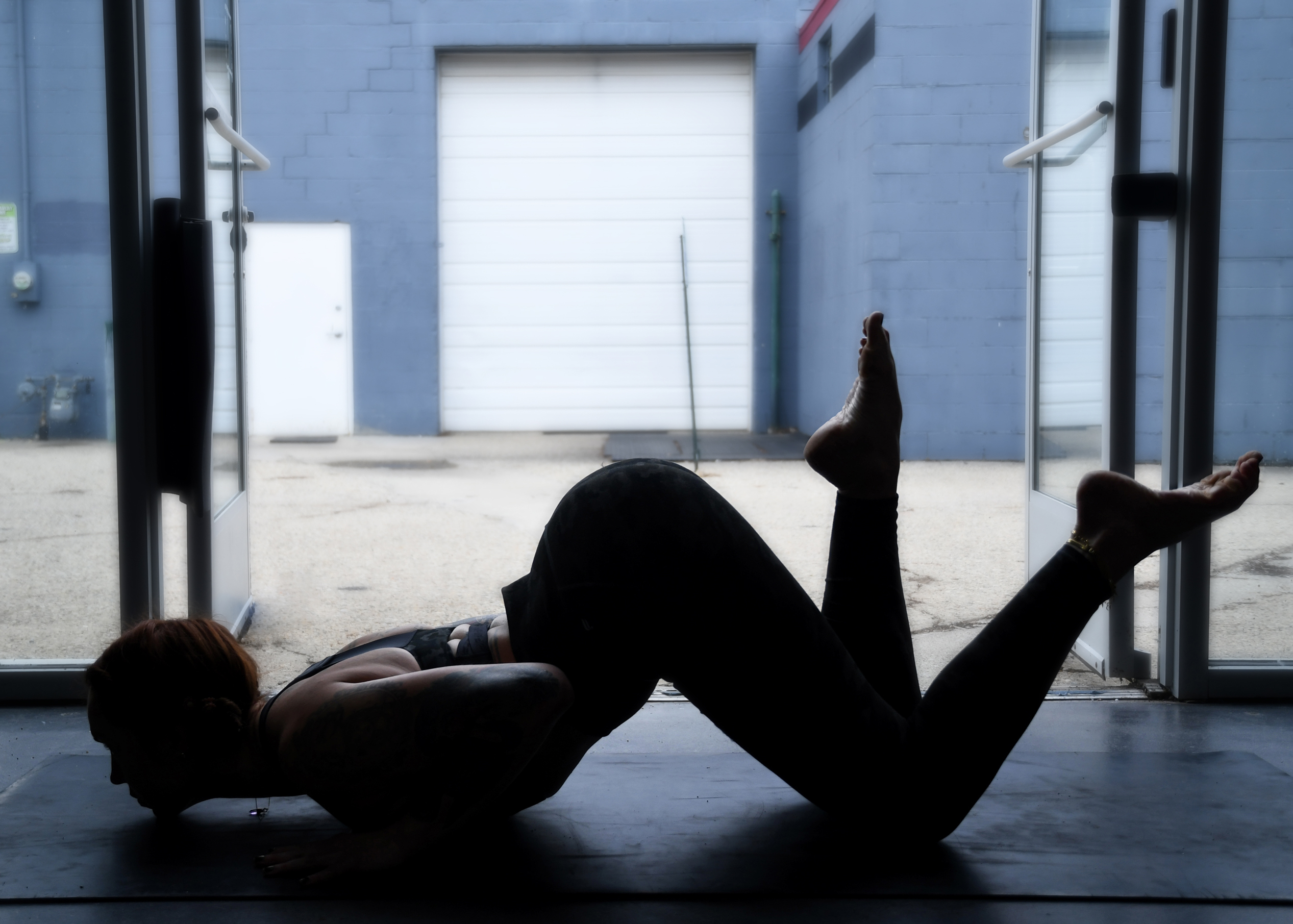 Marta Gruber, a white woman silouhetted by a window practices pranam pose.
