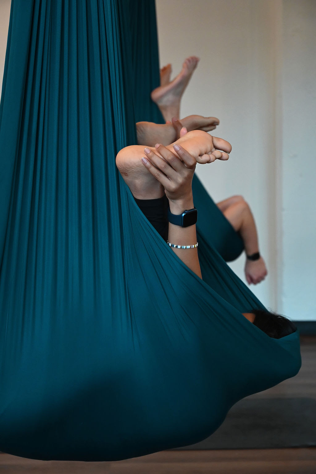 Students practice happy baby pose using the aerial silks.